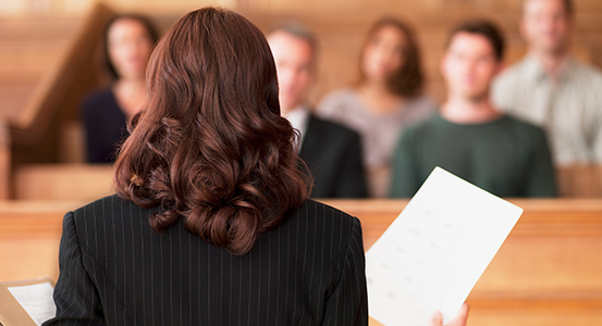 K12 A professional holding a document in a room, with others seated in the background.
