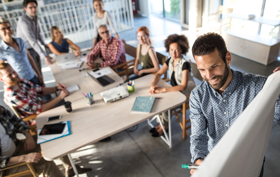 img-CK-Article-600-600-p-L-97 A group of people collaborating in a meeting, with one person writing on a whiteboard.